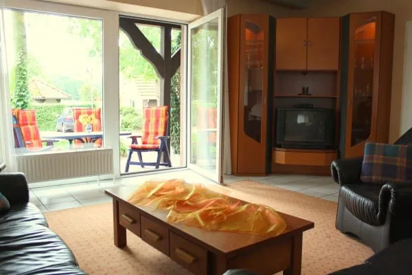 Wohnraum mit Sofa und Couchtisch, große Fenstertür zur Terrasse ins Grüne