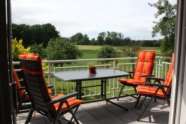 Balkon mit gepolsterten Stühlen, Blick auf Wiesen, Felder und Bäume
