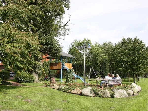 Großer Garten mit Blumenbeet, Bäumen und Sitzgruppe