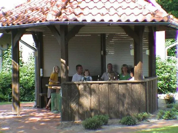 Überdachter Grillplatz aus Holz mit Gästen an der Theke