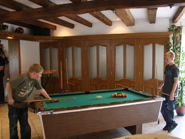 Zwei Jungen spielen Billard im Freizeitraum mit Holzbalken
