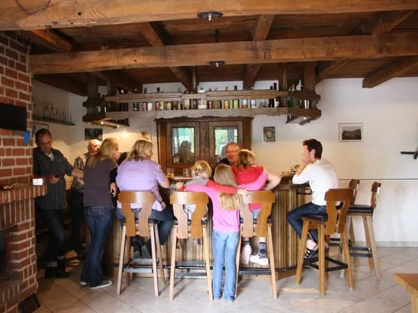 Gäste sitzen auf Barhockern an der Holztheke im Freizeitraum