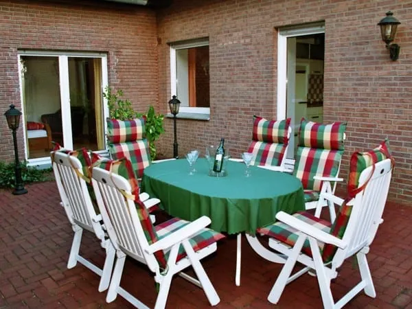 Terrasse mit Gartenmöbeln und gedecktem Tisch vor der Backsteinwand