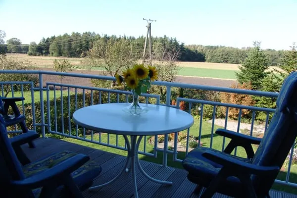Balkon mit rundem Tisch und Sonnenblumen, Blick über Felder bis zum Wald