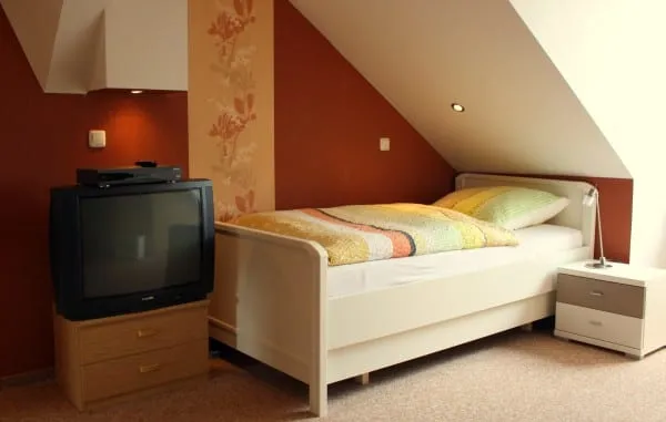 Schlafzimmer unter der Dachschräge mit Bett und Fernseher